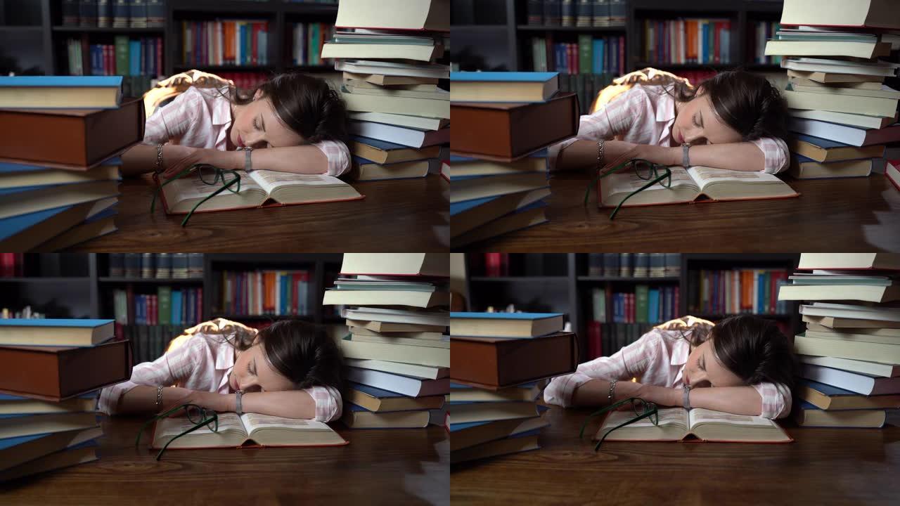 疲倦的女学生在学习期间睡在桌子旁的图书馆里