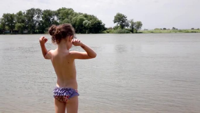 一个小女孩在河岸上向水中扔石头。慢动作