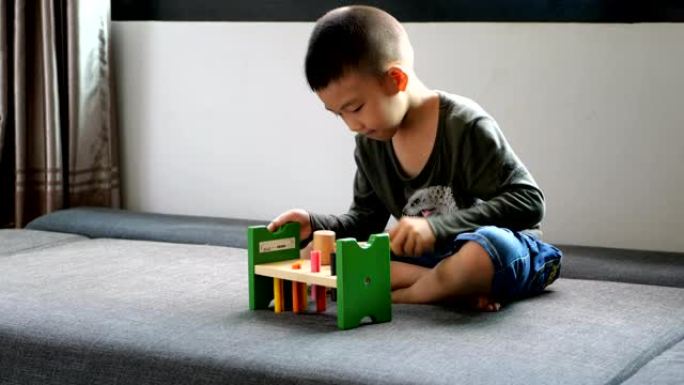 小男孩在沙发上用木锤玩具练习