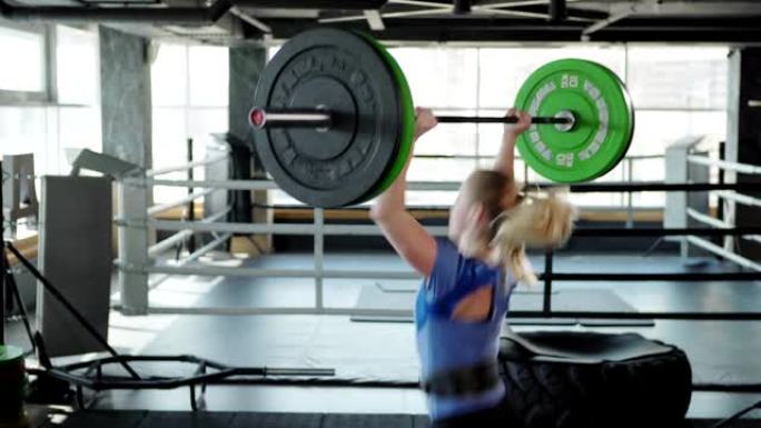 四分之三后视图强壮的女运动员穿着举重带在健身房做挺举运动