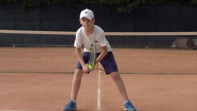 网球训练，有目的的少年男孩在球场上没有球的情况下用球拍练习发球技术，准备比赛