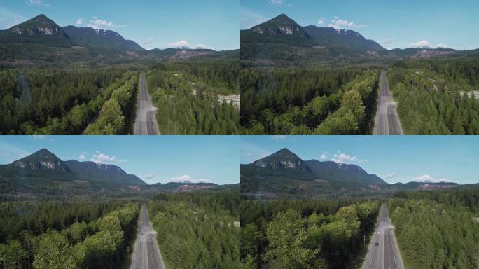 华盛顿州金条附近山区之间森林中繁忙的2号高速公路的鸟瞰图。无人机视频与下降的摄像机运动。