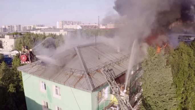 楼梯上的消防员扑灭了一栋住宅高层建筑屋顶的大火。顶视图