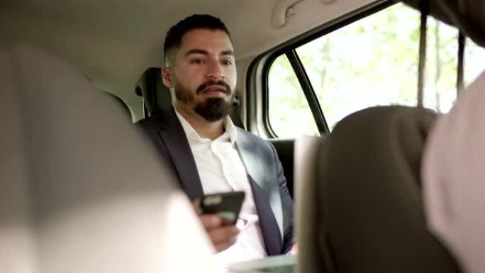 男子在汽车上使用笔记本电脑和智能手机