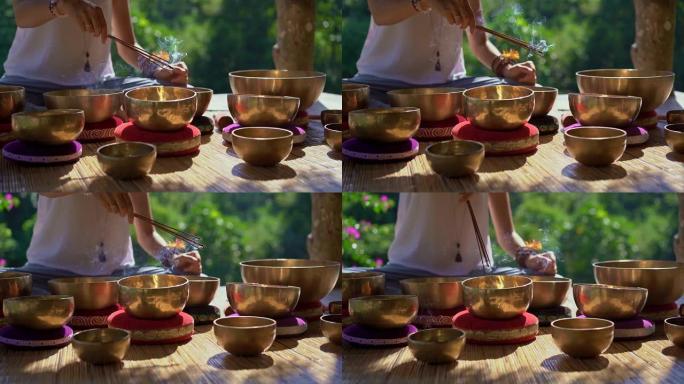 一位亚洲神圣医学大师的超低镜头表演了西藏碗愈合仪式。用藏族歌唱碗冥想。她坐在凉亭里冥想，背景是美丽的