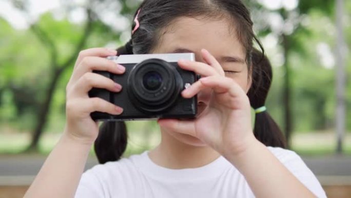 亚洲小女孩用相机拍摄大自然。技术理念，拍照体验生活。4K分辨率和慢镜头。