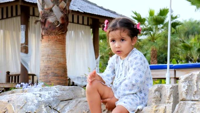 可爱的小女孩坐在沙滩上自言自语。