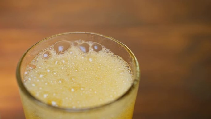 橙色柠檬水倒入带有冰块的冷玻璃杯中