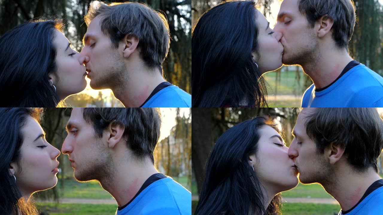 年轻迷人的恋人在日落时在公园接吻。浪漫，调情，吸引力