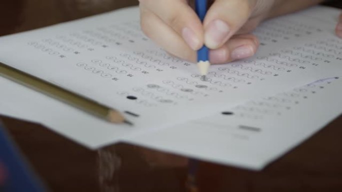 学校/大学的学生在化学教室里用手拿铅笔在光学表格上写试卷，在桌子上做期末考试。