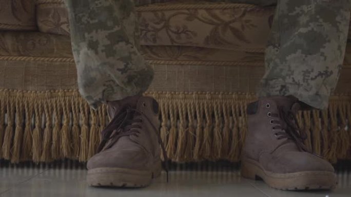 穿着军鞋的士兵的脚，坐在旧沙发上