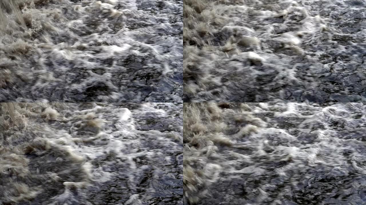 极度接近涌入河中的浑浊冒泡水流。小瀑布。特写。4K。