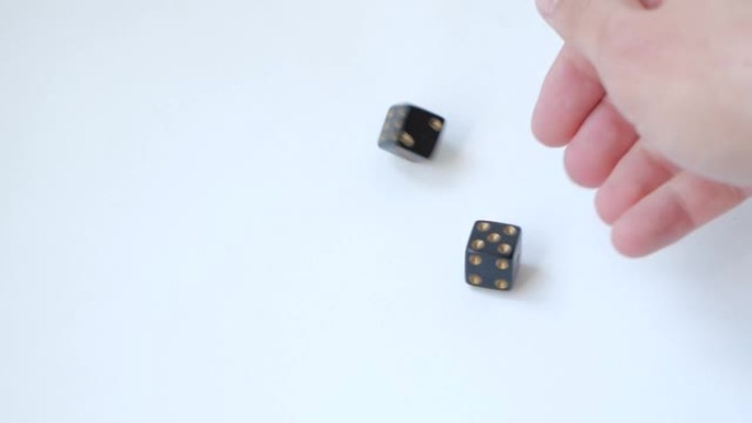 用一对黑色赌博骰子在白色桌子上慢动作滚动一个和一个五