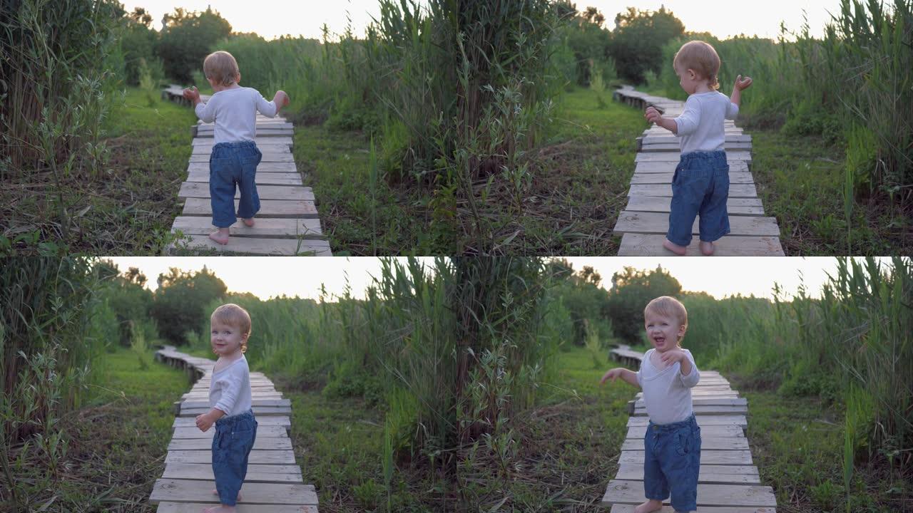 开朗的蹒跚学步的男孩赤脚走在绿草丛中的木桥上