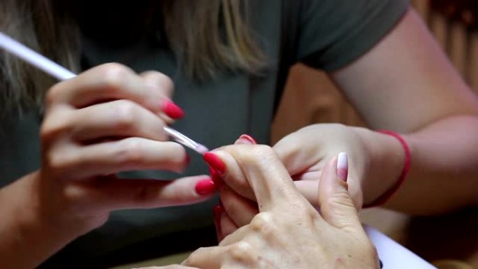 女性指甲画。美甲大师用客户端食指指甲上的刷子创建渐变。特写视图。