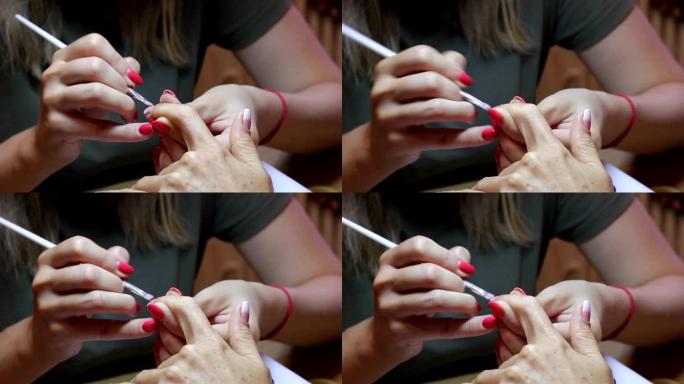 女性指甲画。美甲大师用客户端食指指甲上的刷子创建渐变。特写视图。