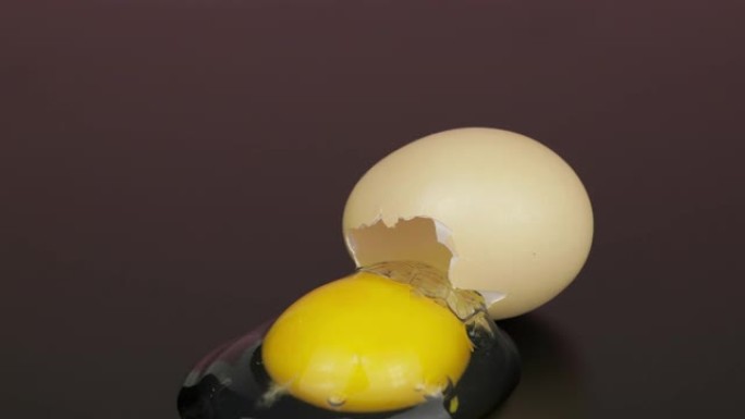 从黑色表面的破碎蛋壳中倒出的蛋黄