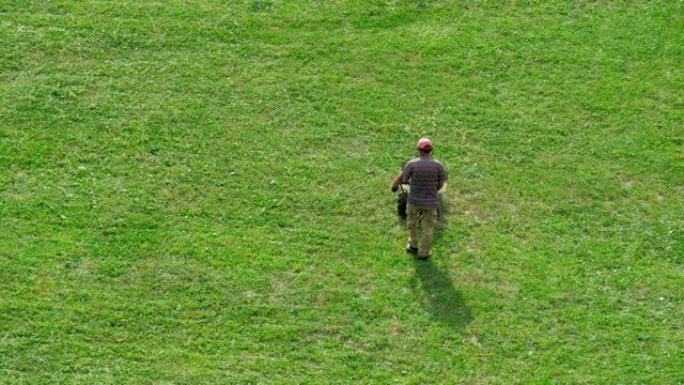 一个人在一个大草地上用割草机割草。
