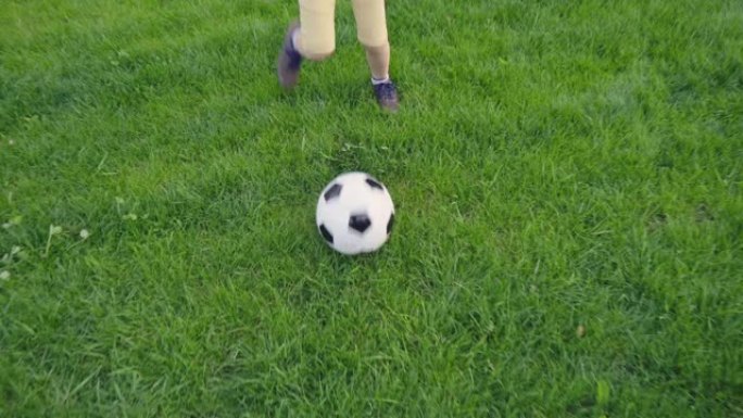 踢足球的男孩。带球的孩子穿过绿草