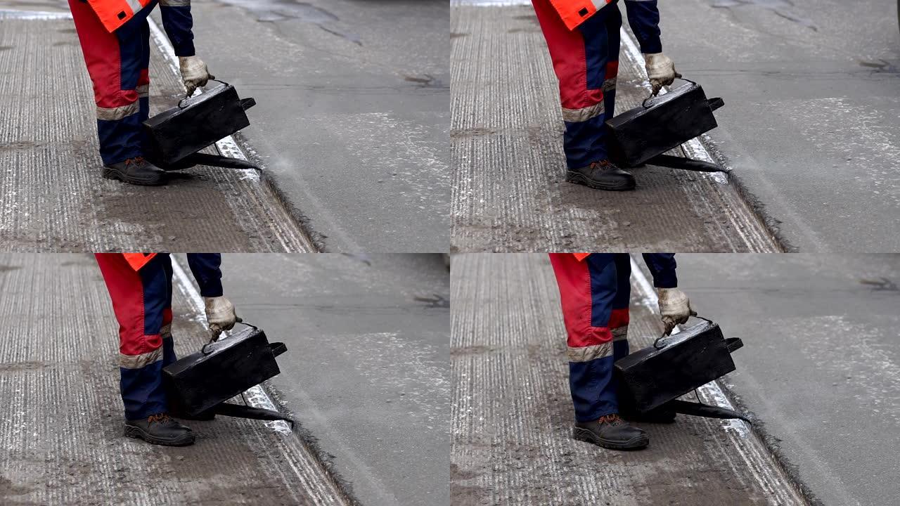 路修。工作细节，工人浇筑树脂路面以覆盖沥青。