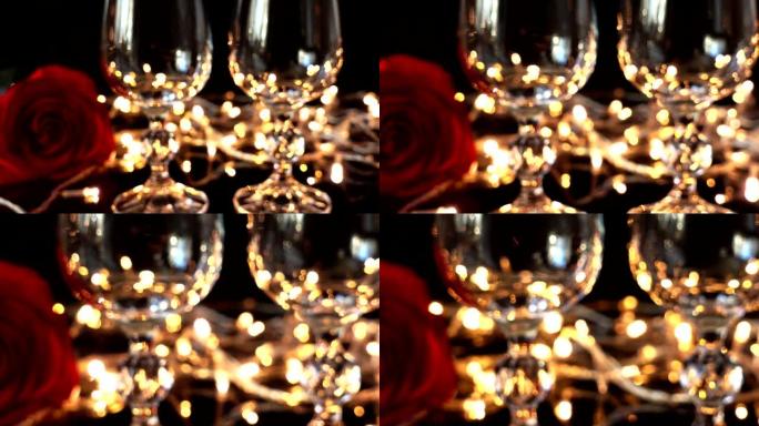 酒杯和玫瑰在明亮的花环的背景下。注意力不集中。