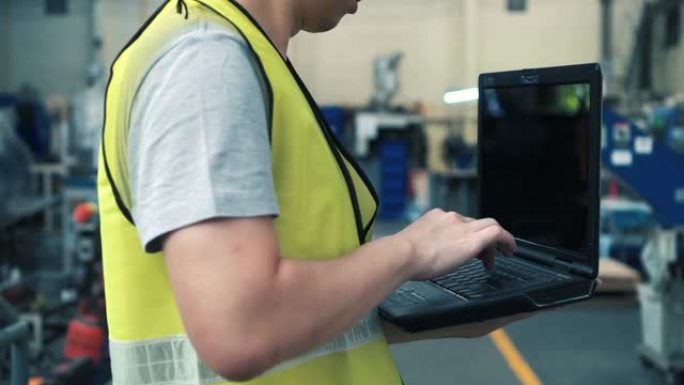 带安全帽的工业工程师在工厂使用笔记本电脑