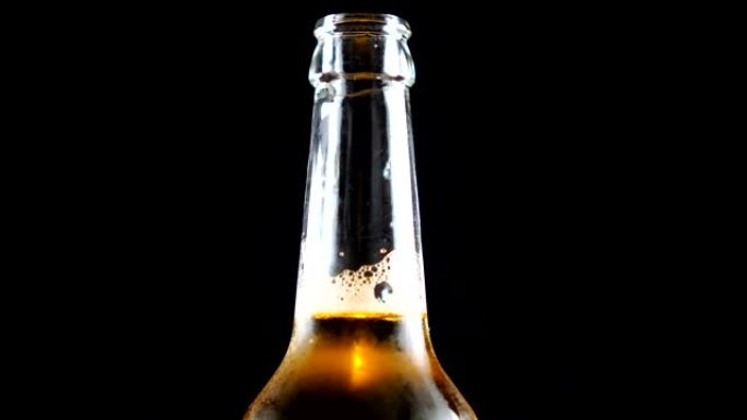 啤酒瓶特写。瓶装淡啤酒在黑色背景上旋转。