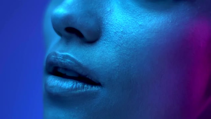 工作室彩色霓虹灯中未来派时装模特嘴唇的特写镜头。