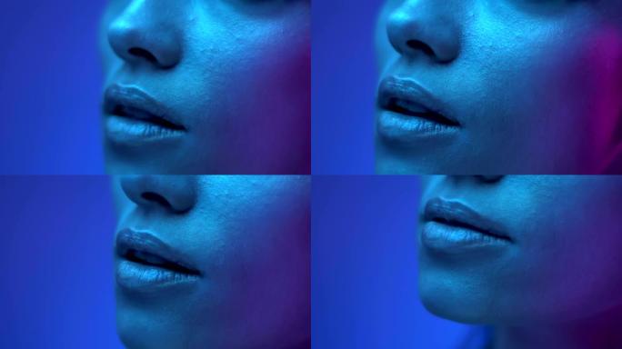 工作室彩色霓虹灯中未来派时装模特嘴唇的特写镜头。