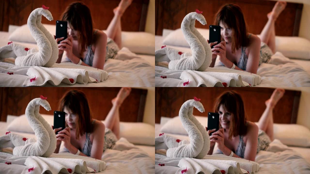 女孩在电话上拍了一张用毛巾制成的天鹅的照片
