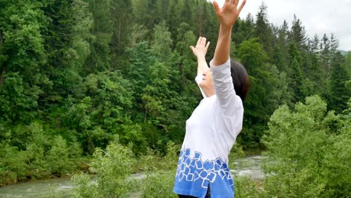 高级妇女在森林和山脉的景观上对上臂进行伸展运动