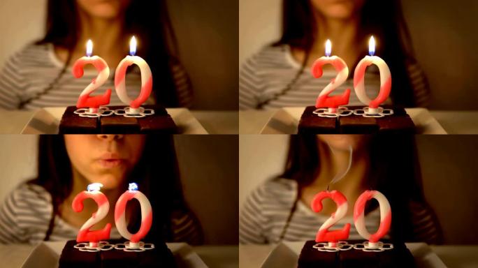 快乐的少女庆祝自己的20岁生日，并在室内自制烤蛋糕上吹蜡烛