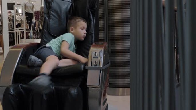 一个无聊的男孩在商场的按摩椅上