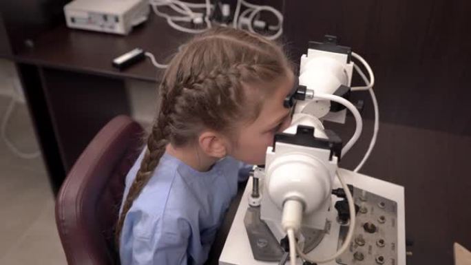 一位眼科医生使用眼科检查设备检查小女孩视力的俯视图