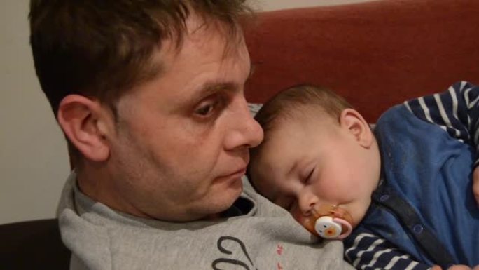 疲倦的父亲让他六个月大的男婴入睡