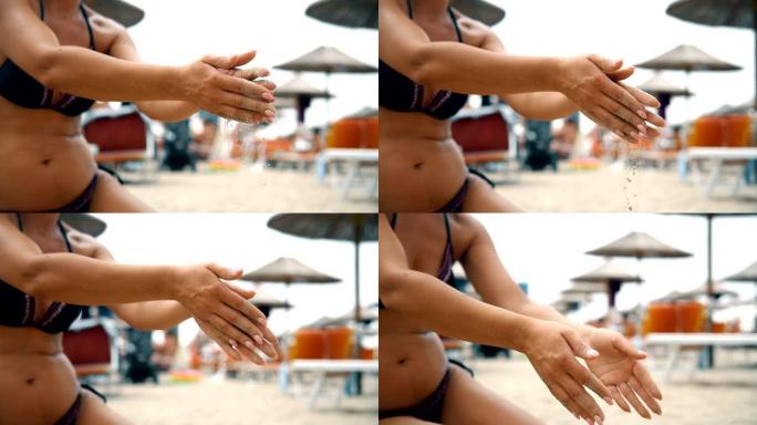穿着比基尼的迷人女人在慢动作中从沙滩上干净的手