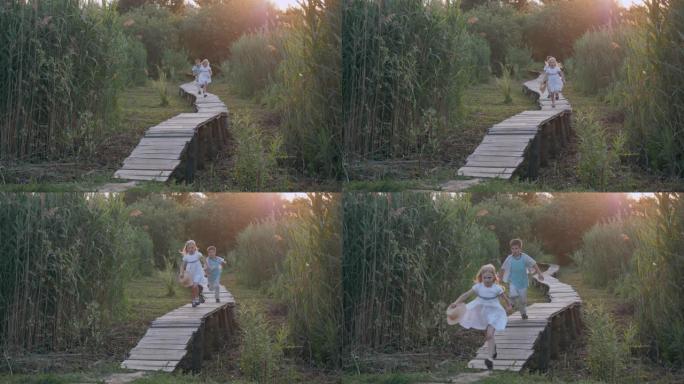 儿童娱乐，可爱的孩子朋友男孩和女孩在大自然的绿色植被中追赶并在木桥上奔跑