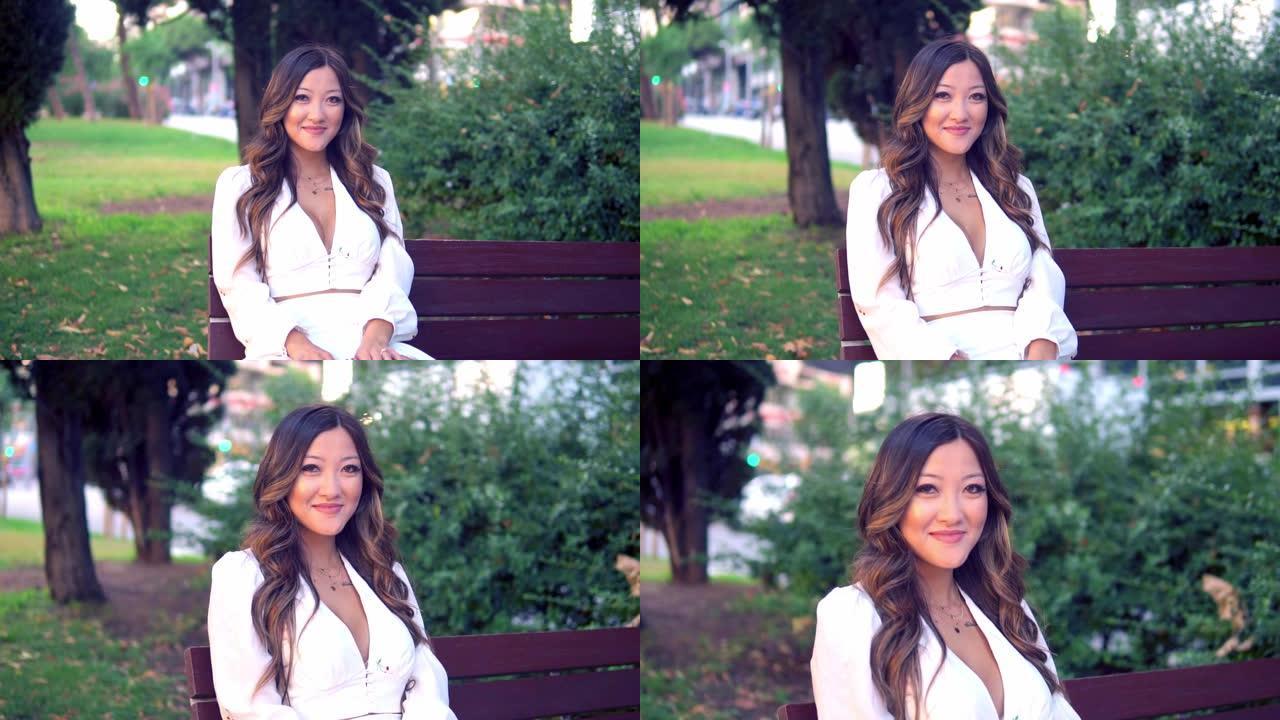穿着白色连衣裙的美丽亚洲女孩在公园微笑
