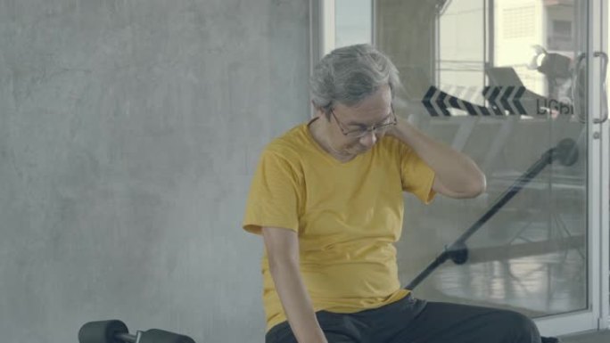 亚洲老人劳累后在健身房锻炼，亚洲老人出汗后坐表情疲惫，在健身后呼吸，生活方式健康健康的理念。