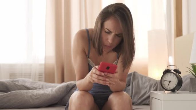 穿着睡衣的女人打着哈欠，在床上用手机