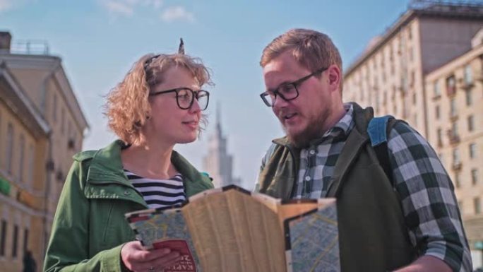 迷恋的芬兰夫妇度蜜月环游世界。年轻美丽的游客带着地图环游世界。两个游客看着地图，寻找路线。