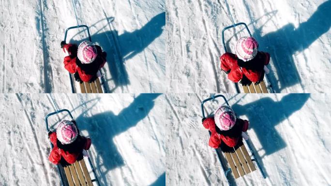 小女孩的俯视图，冬天在公园里雪中滑雪的孩子，生活方式跟踪镜头