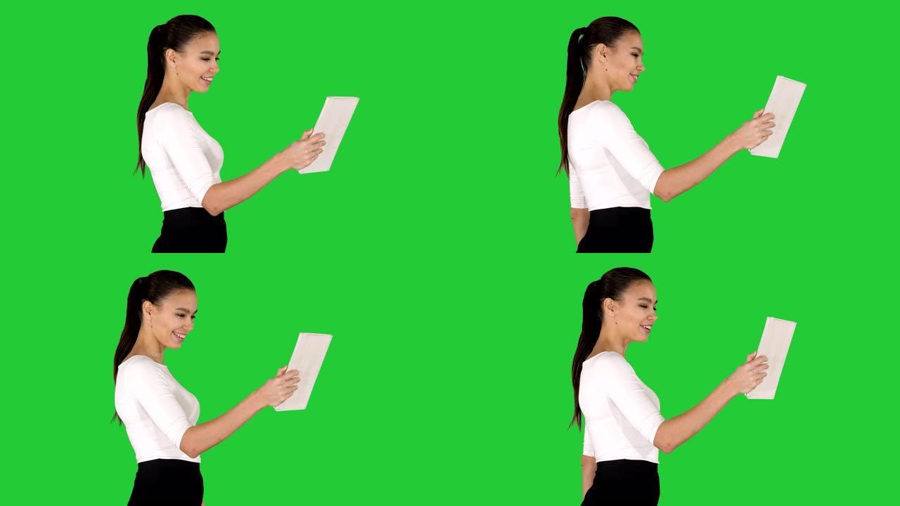快乐的女人用绿色屏幕的平板电脑进行视频通话，色度键