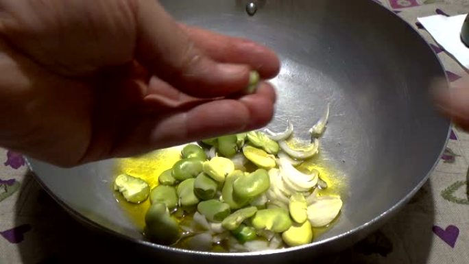 洋葱调味料和橄榄油油炸新鲜蚕豆。