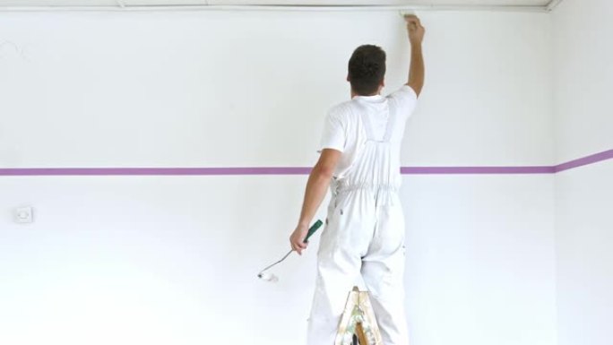 画家站在梯子上粉刷墙壁