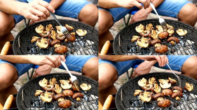 男人翻过美味的香菇蘑菇，它们在烧烤时烤过煤。