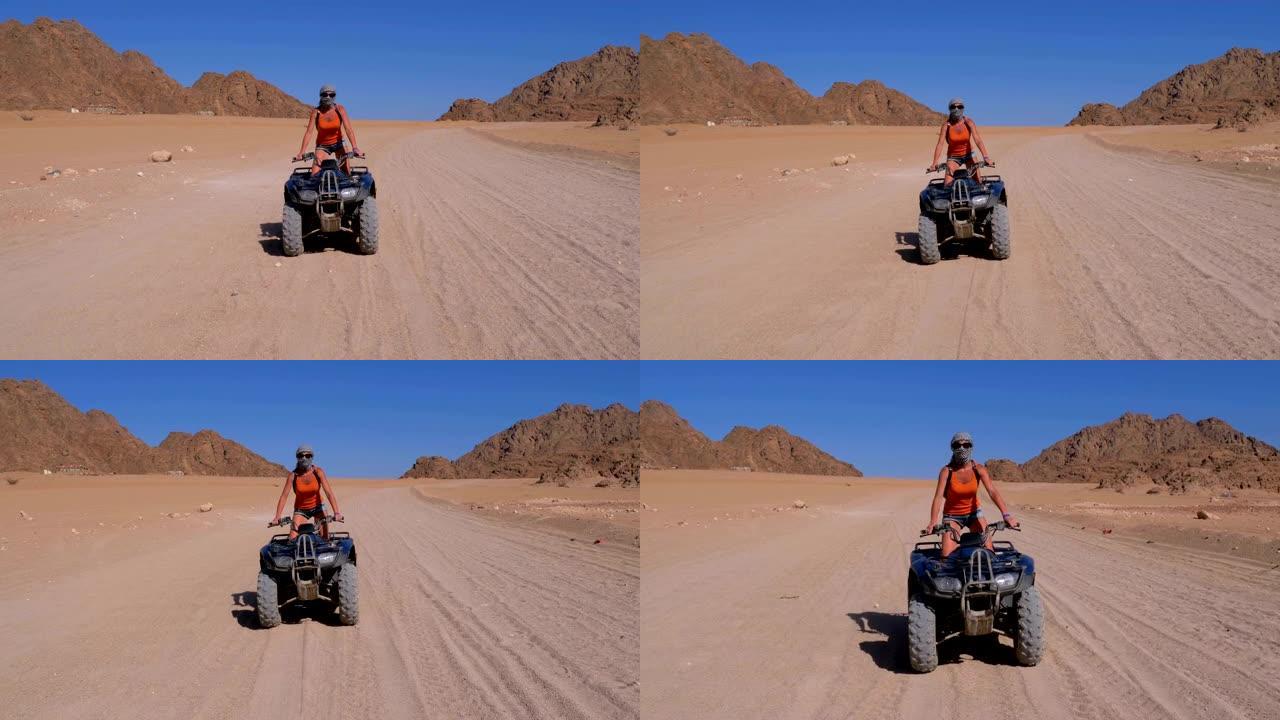 骑四轮摩托的女孩在群山背景下穿越埃及的沙漠