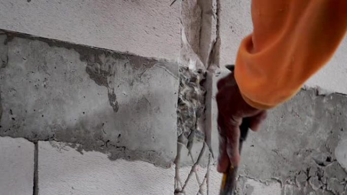工人们正在使用锤钻来提取混凝土墙