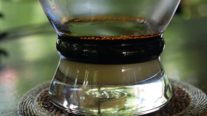 在咖啡馆使用越南传统的phin过滤器用牛奶煮咖啡。咖啡在玻璃杯中慢慢滴落。Ca phe sua da