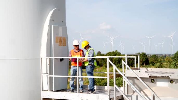 技术人员检查风力涡轮机的状况并向电气工程师报告。